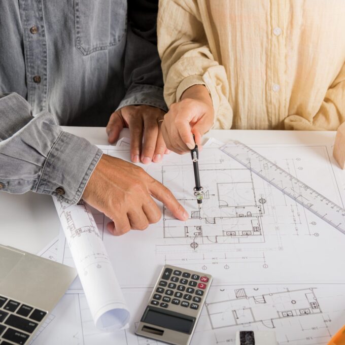 Two engineers pointing at drawings project, Architect team meeting consult and work for architectural construction project working with partner and engineering after editing on blueprint paper plans